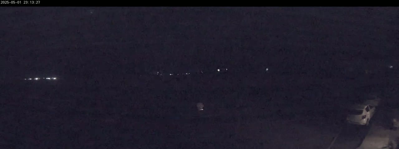 A long line of faint headlights is visible in the distance on a dark, nighttime scene.