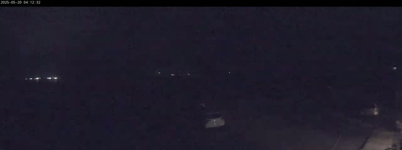 A dark, nighttime scene shows a few distant headlights and a single vehicle in the lower center.
