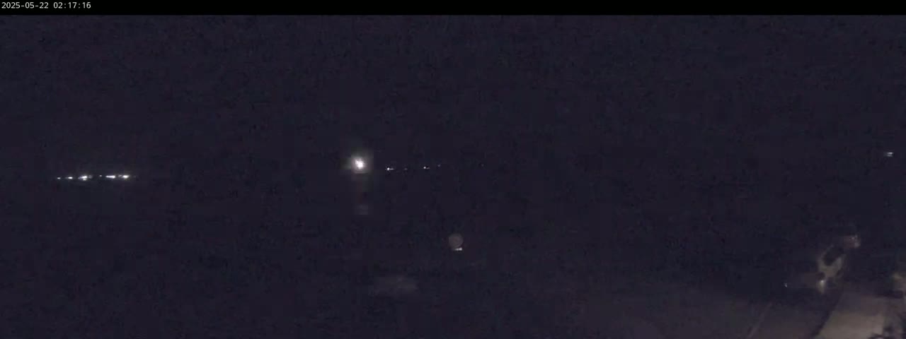 A dark, nighttime scene shows a few distant lights and a road curving into the darkness.