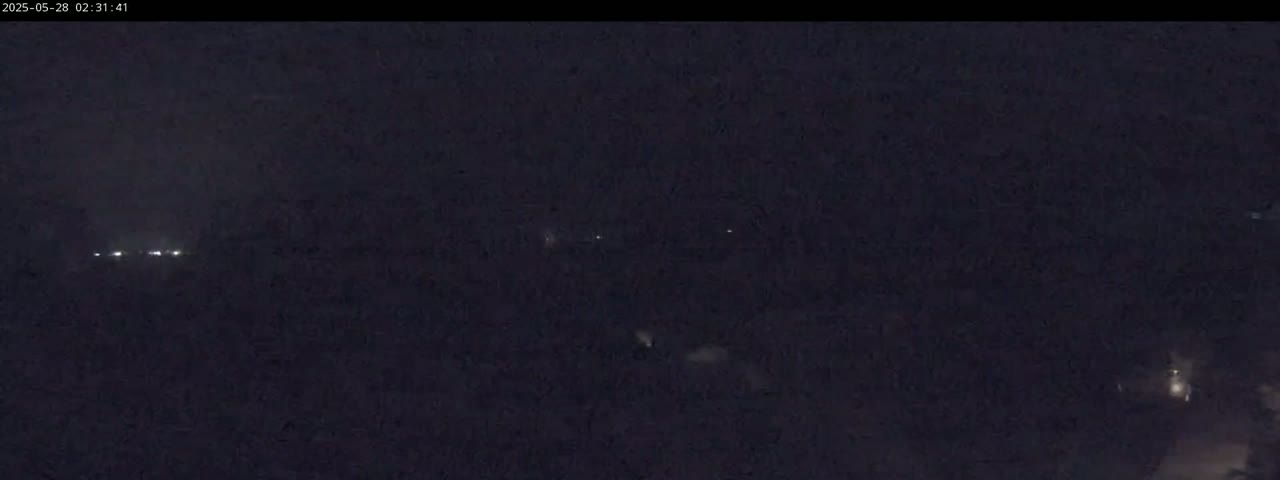 A nighttime, dark scene shows a few distant lights in the far background.