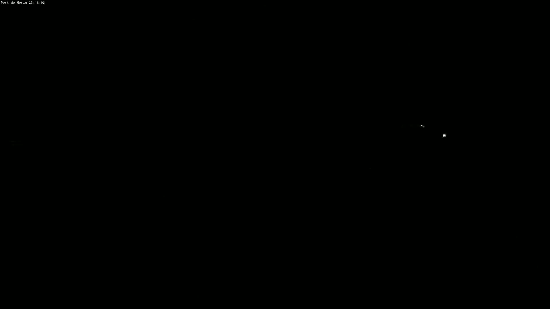 A nighttime image shows a few faint lights in the distance against a completely dark sky.