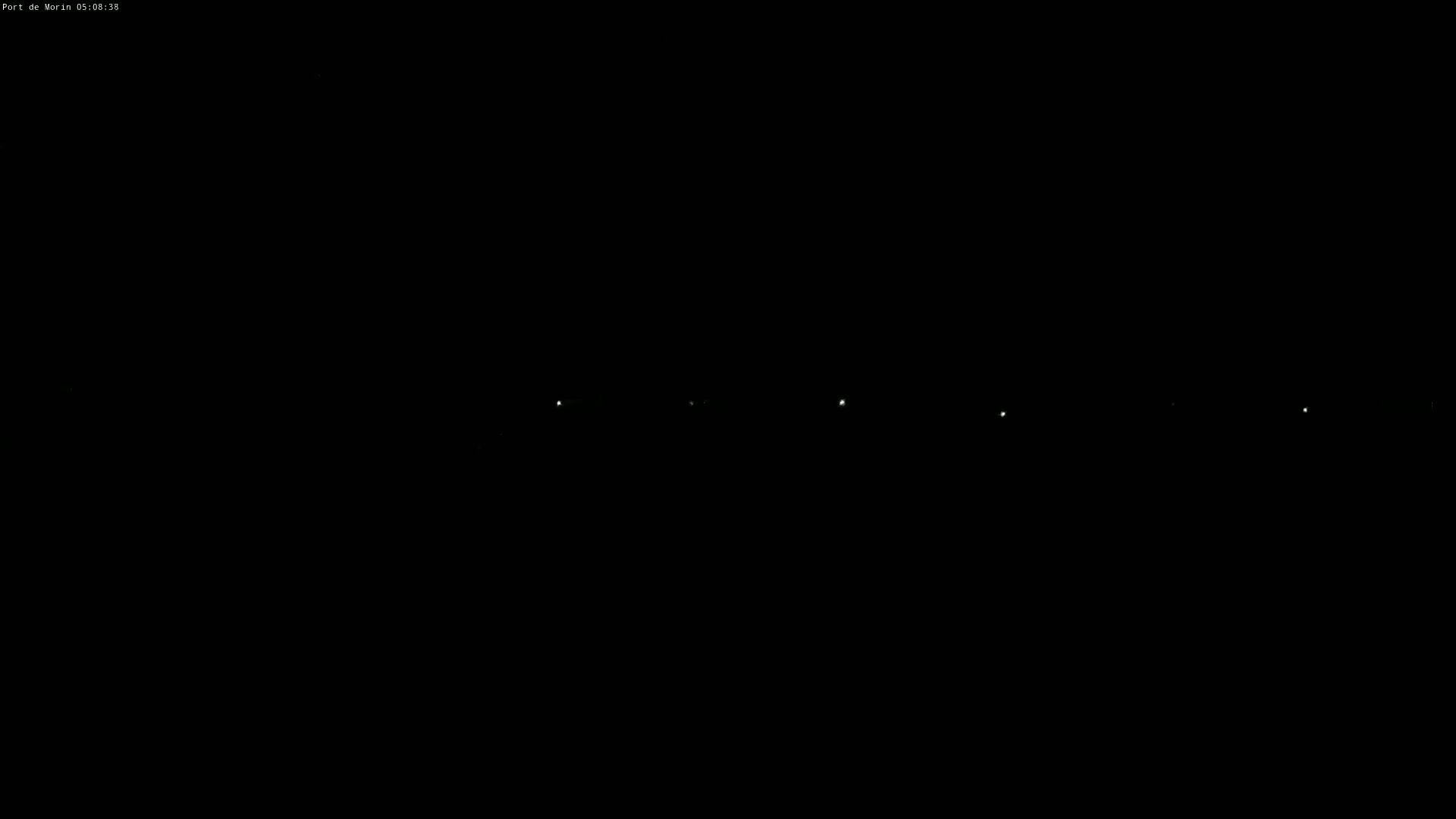 A nighttime, dark scene shows a line of distant lights.