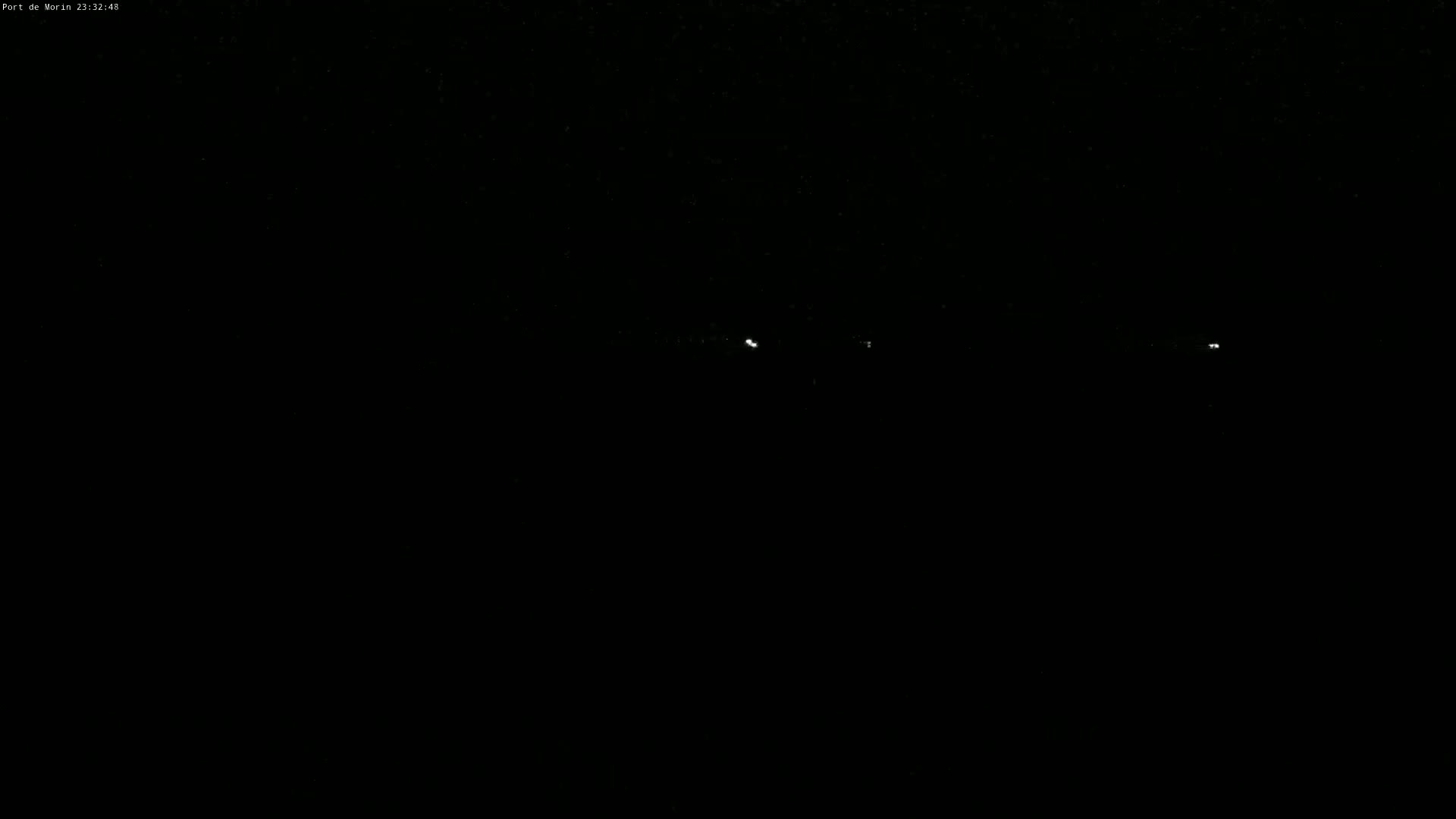A dark, nighttime scene shows a few faint lights in the distance.