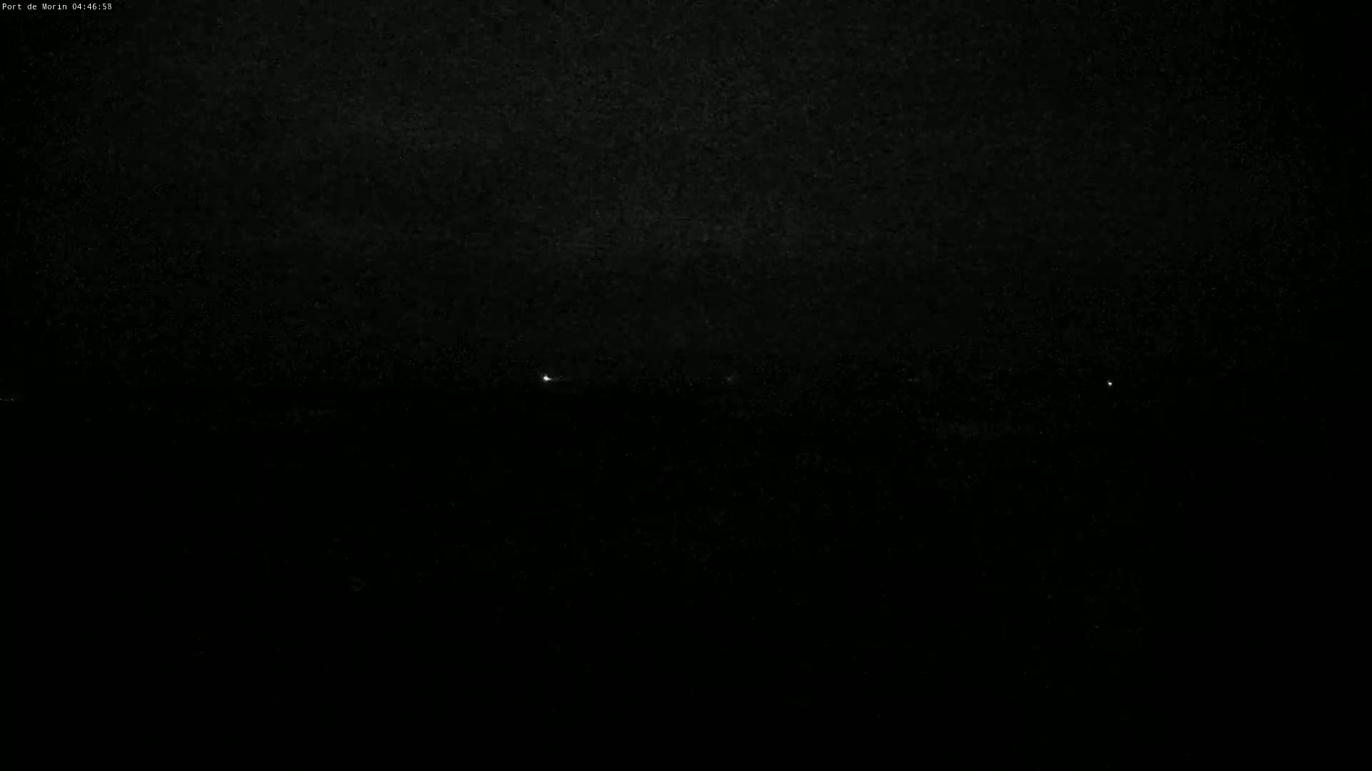 A dark, nighttime scene shows a few faint lights on the horizon.