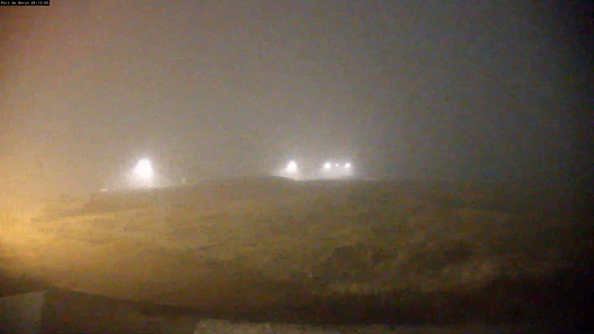 A foggy, dimly lit landscape is visible at night, with several distant lights faintly illuminating the scene.