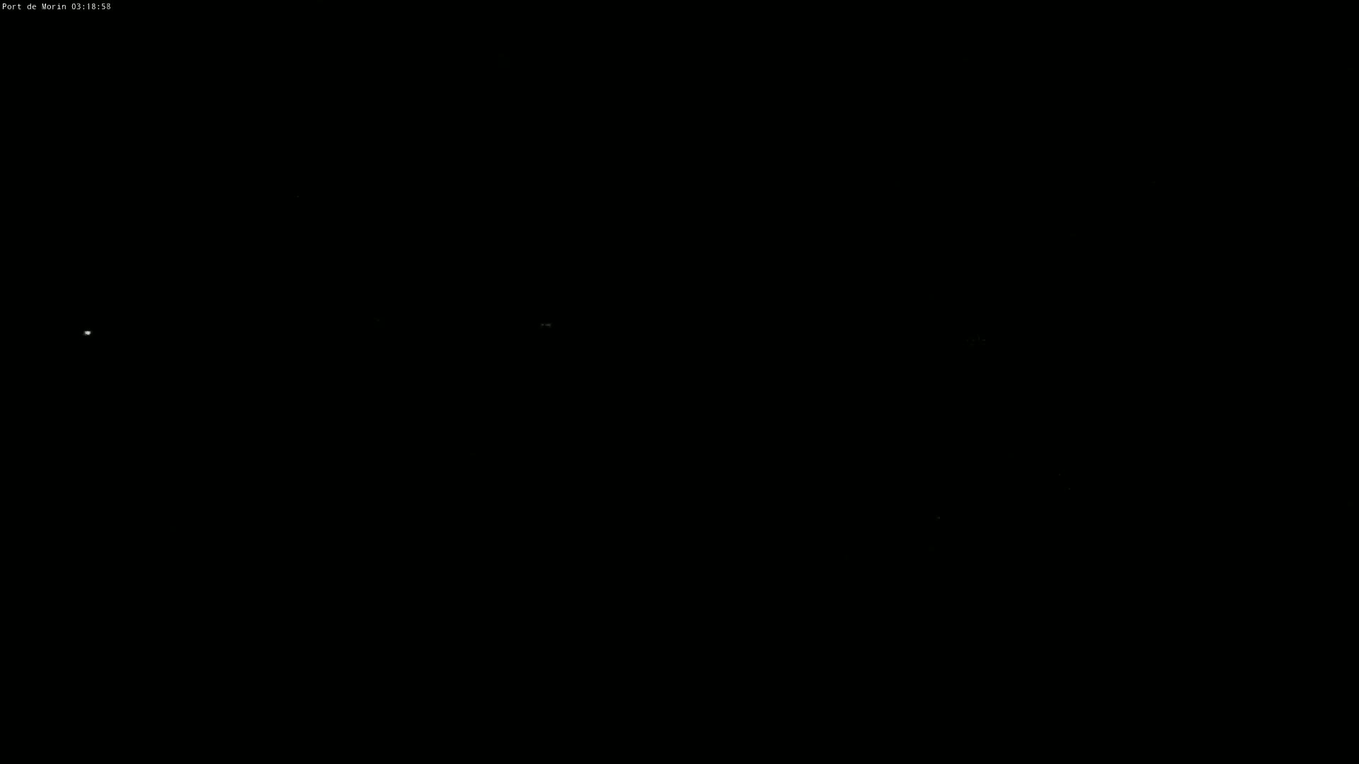A dark, nighttime scene shows a few faint lights in the distance.
