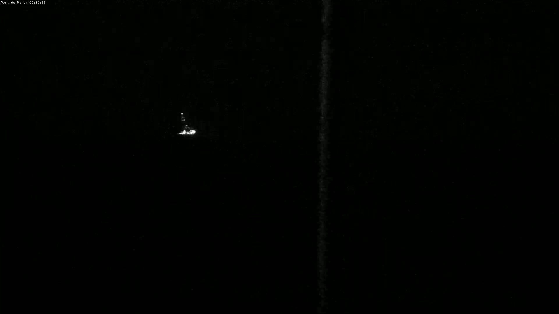 A small, bright light is visible in the distance against a completely dark, nighttime sky.