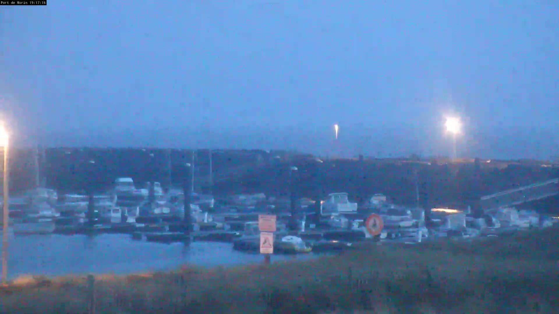 A marina filled with numerous boats is visible at dusk under a clear, twilight sky.