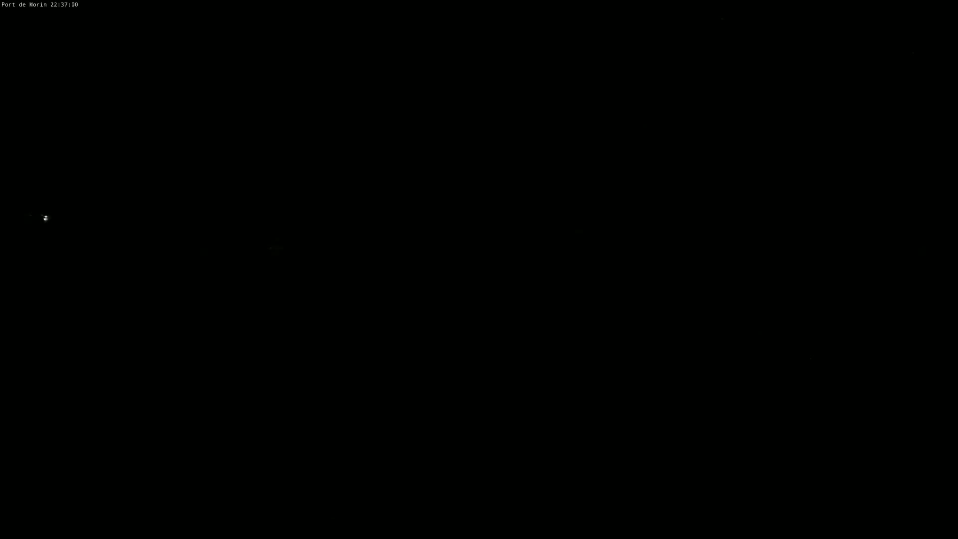 The image shows a completely dark nighttime scene with two faint lights visible in the distance.