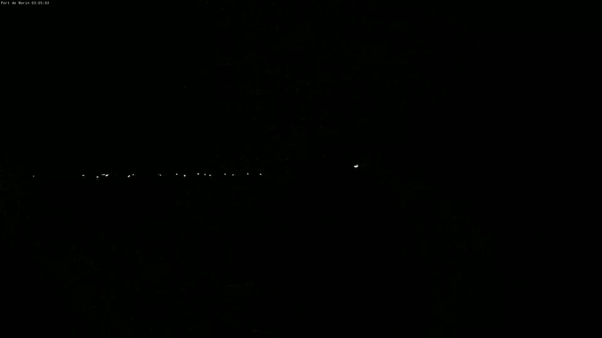 A nearly-black nighttime scene shows a line of distant lights in the far horizon.