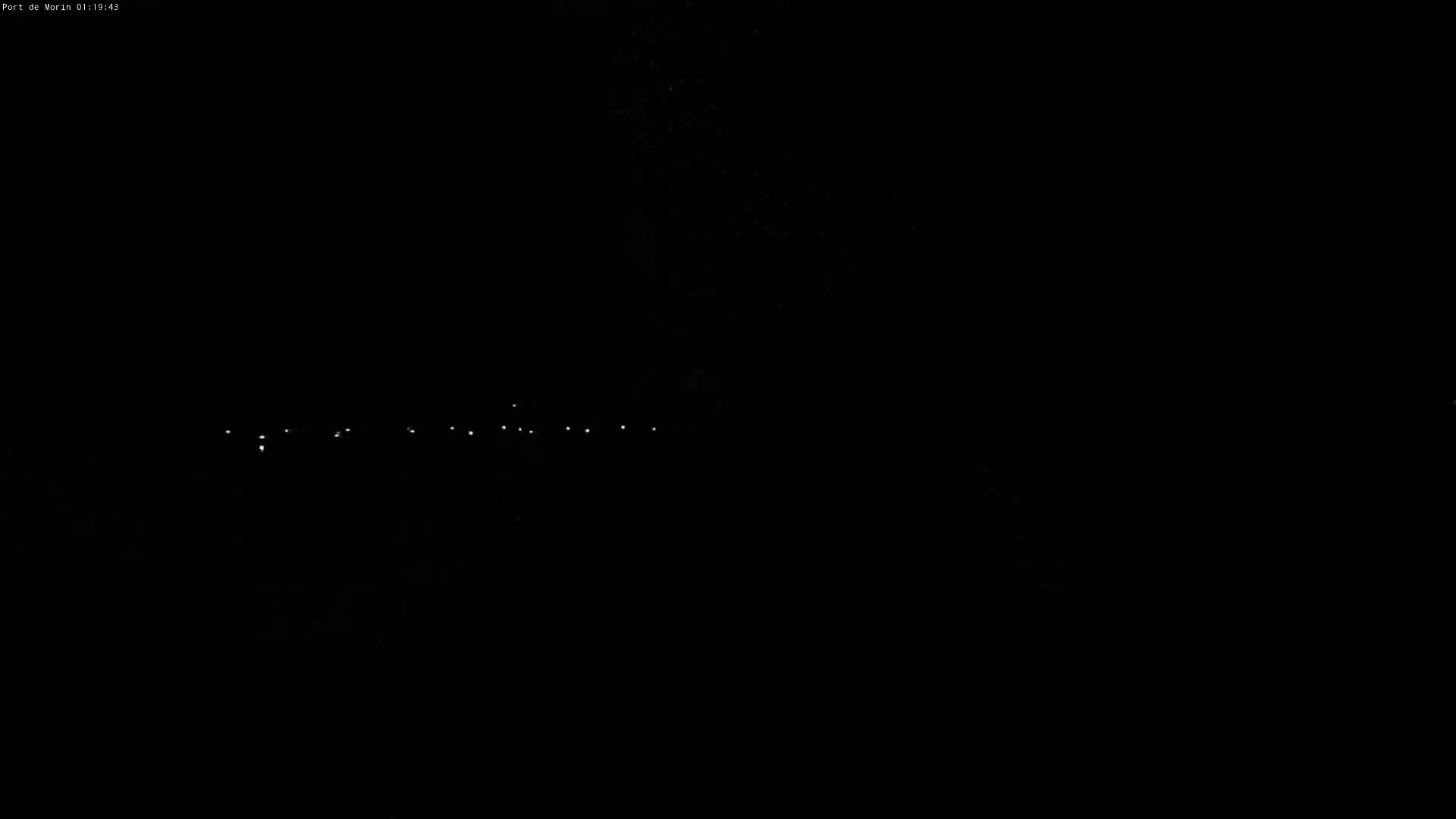 A dark, nighttime scene shows a row of small, distant lights.