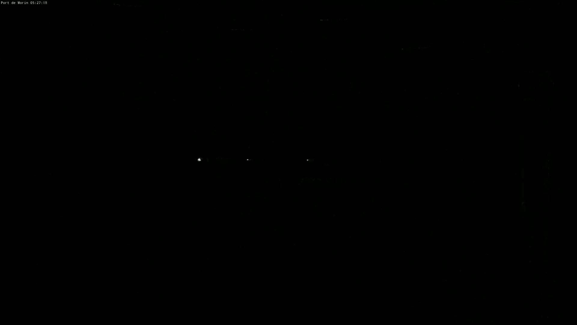 A dark, nighttime scene shows a few faint lights in the distance.