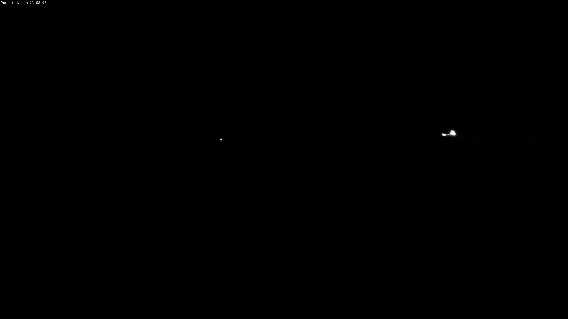 A nighttime image shows three small, bright lights in the distance against a completely dark sky.