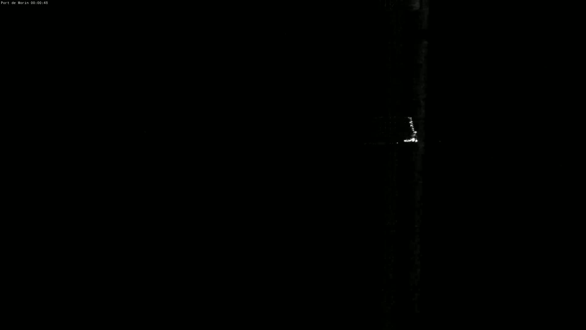 A dark, nighttime scene shows a vertical, bright streak of light against a mostly black background.