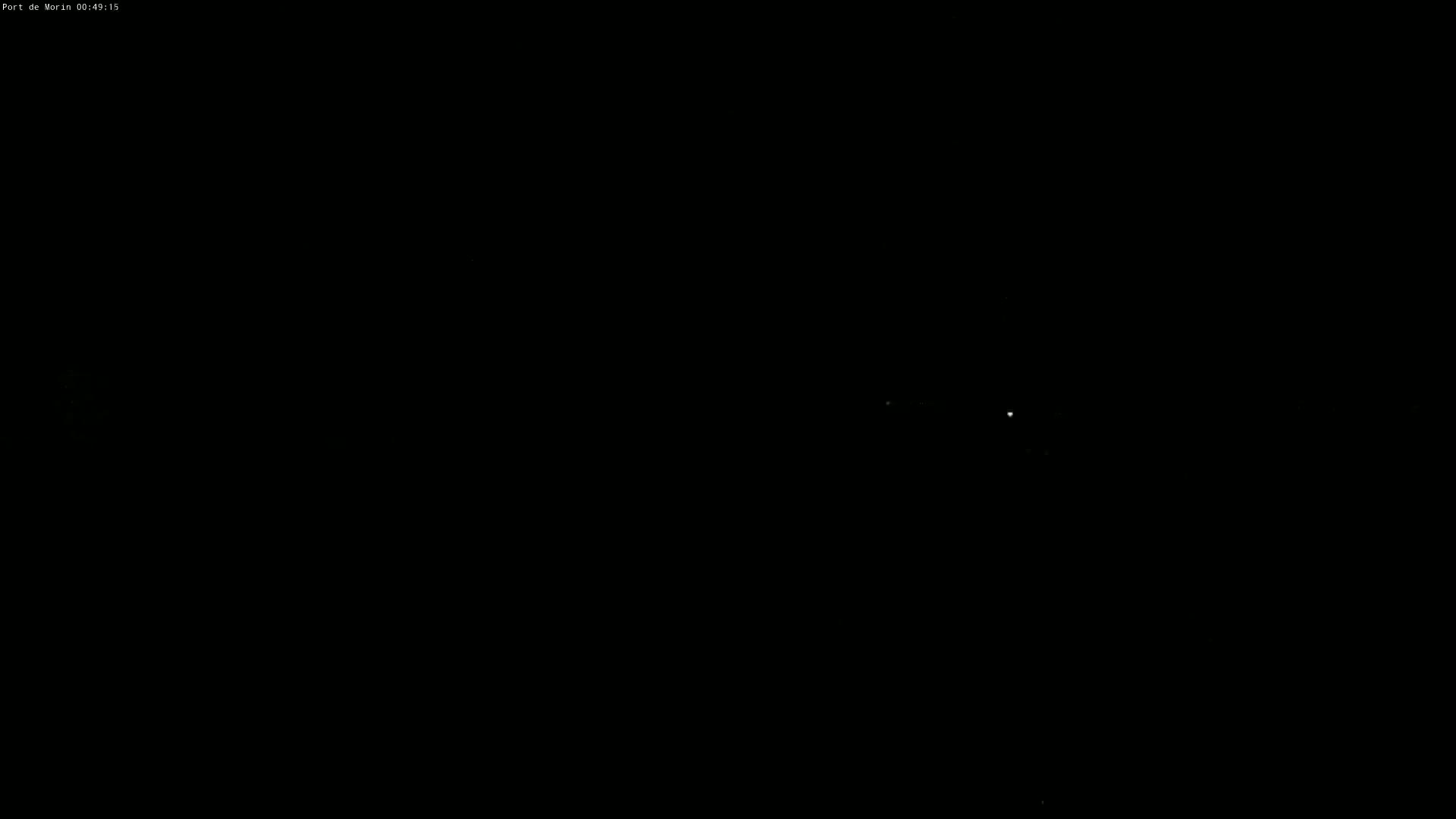 A mostly dark image shows a few faint lights in the distance at night.