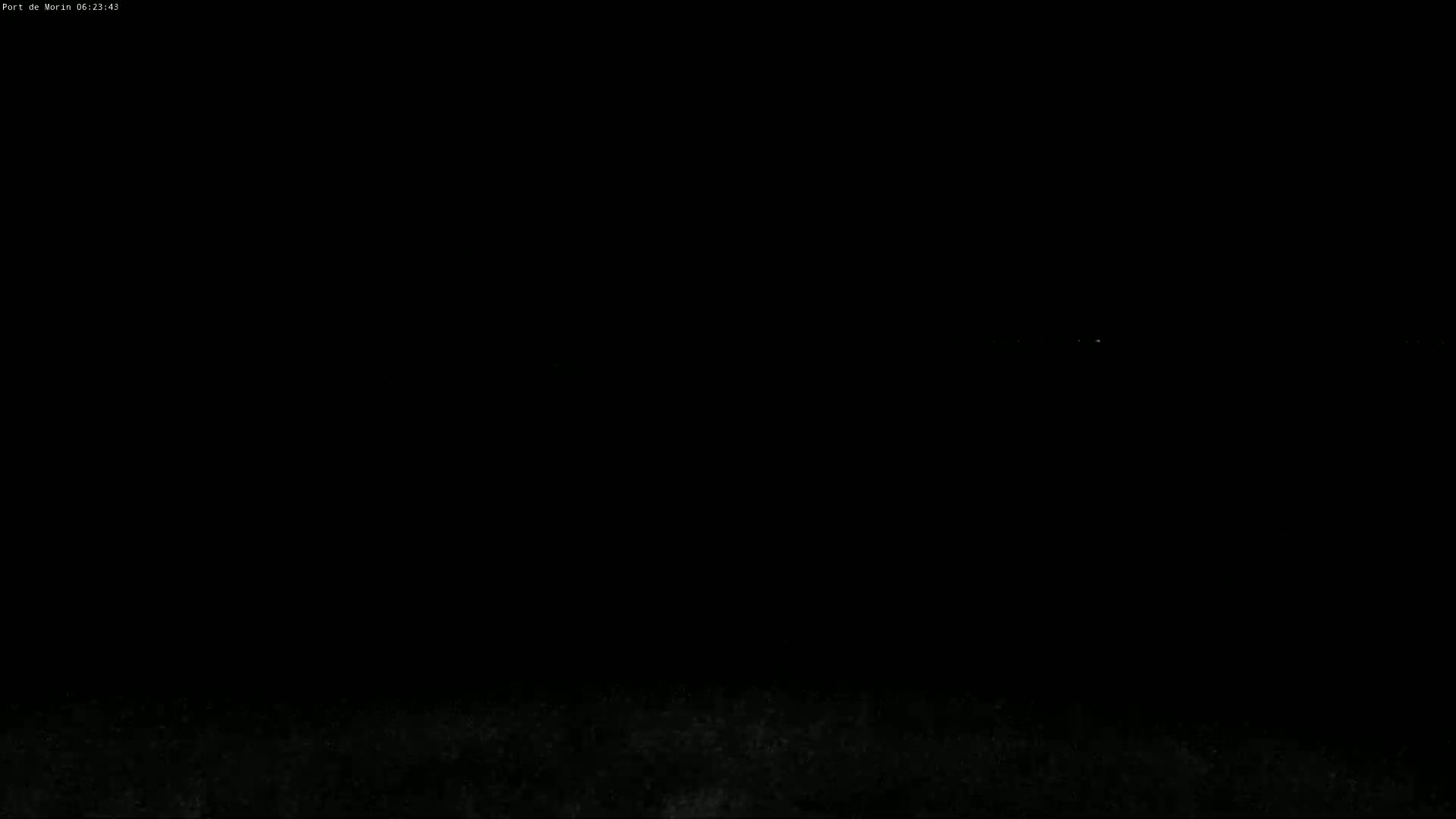 A dark nighttime scene shows a faint, distant glow on the horizon.