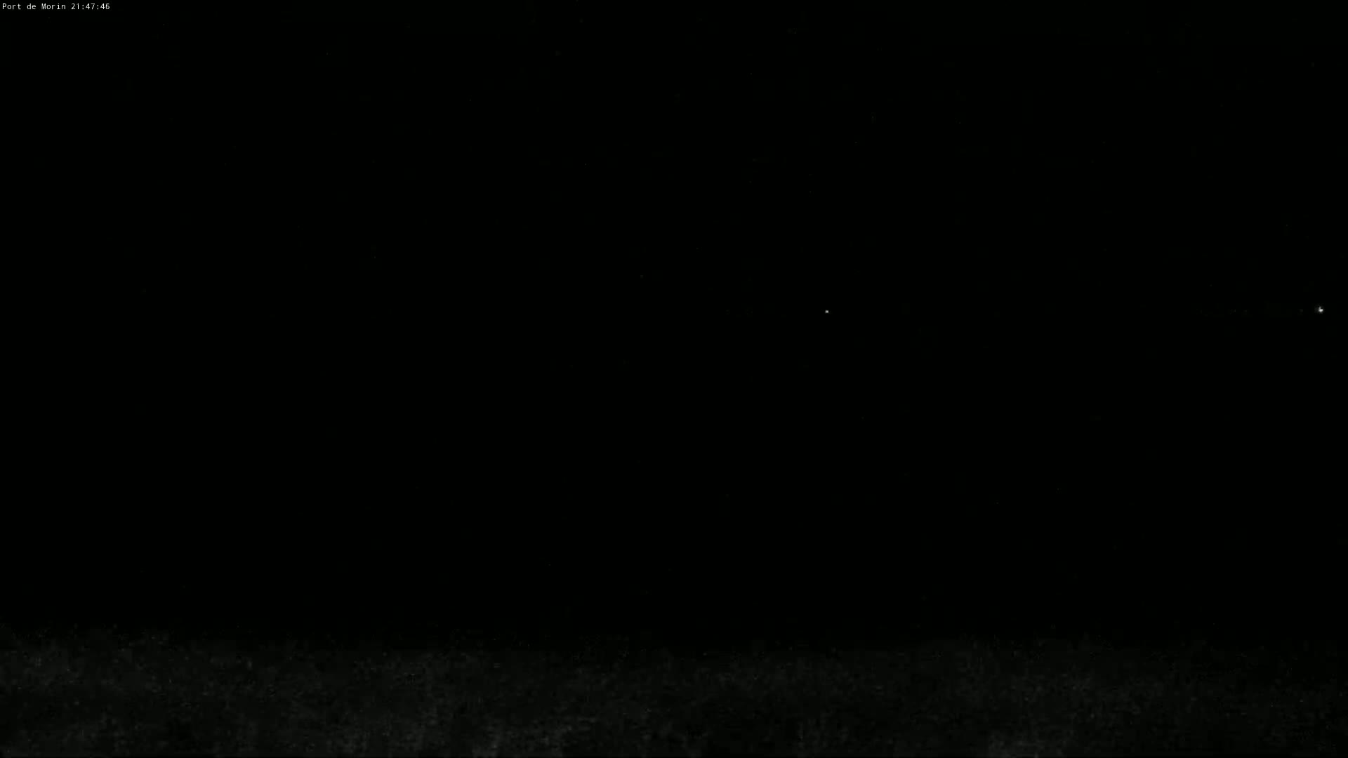 A dark, nighttime scene shows a few distant lights against a mostly black sky.