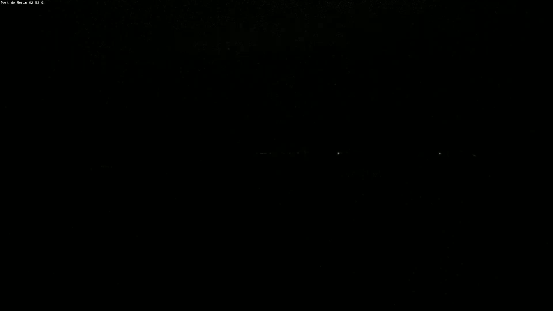 A dark, nighttime scene shows a faint line of distant lights.