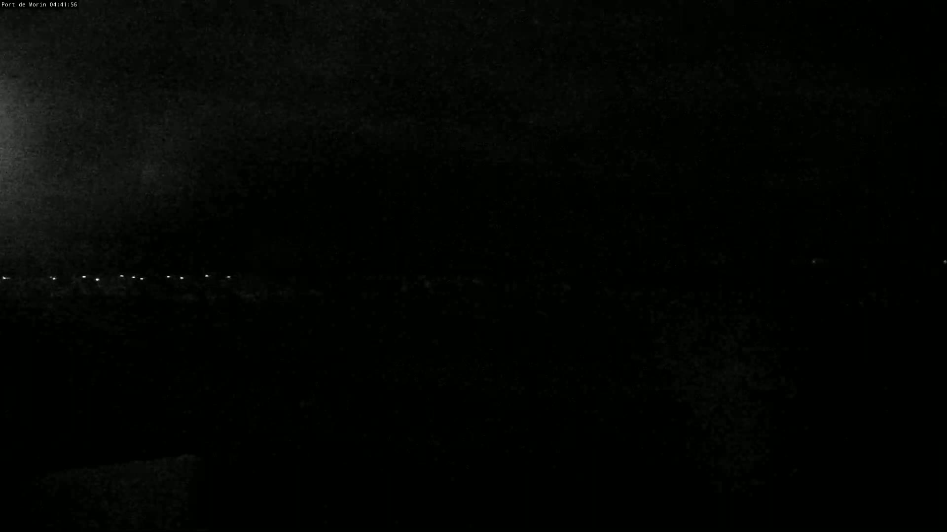 A dark, nighttime scene shows a faint line of distant lights on the horizon.