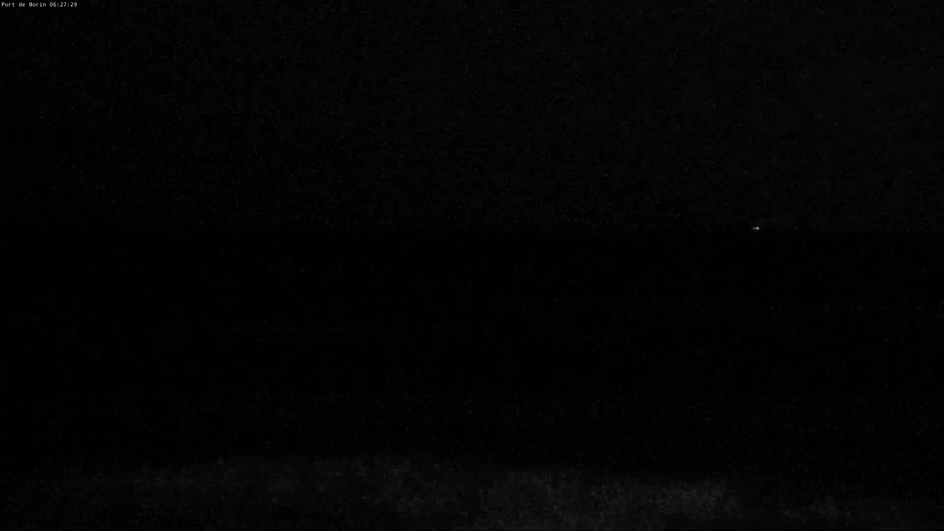 A dark, nighttime scene shows a single, faint light in the distance over a dark horizon.