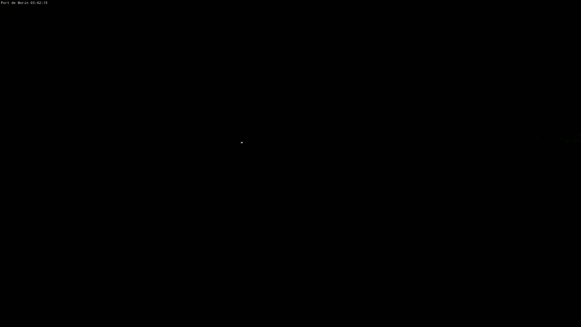 A small, faint light is visible in a completely dark nighttime sky.