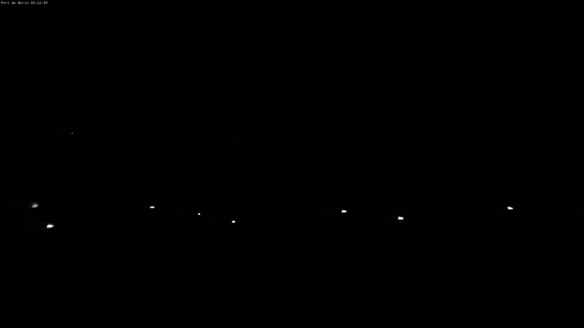 A nighttime view shows several faint lights in the distance against a completely black sky.