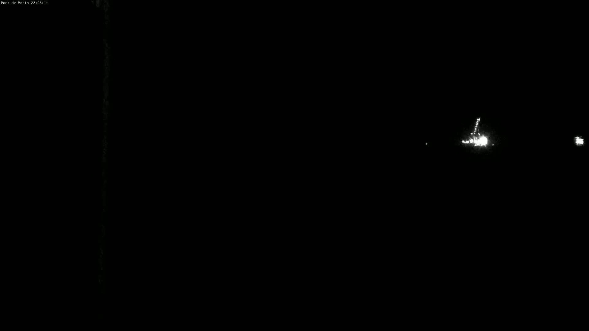 A nighttime long shot shows a few distant bright lights in the darkness.