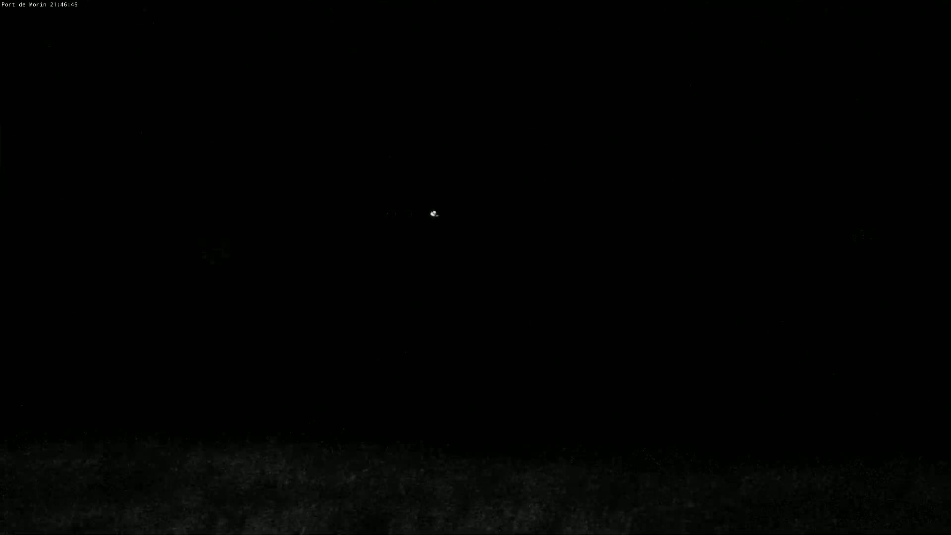 A dimly lit, nighttime outdoor scene shows a faint light in the distance.