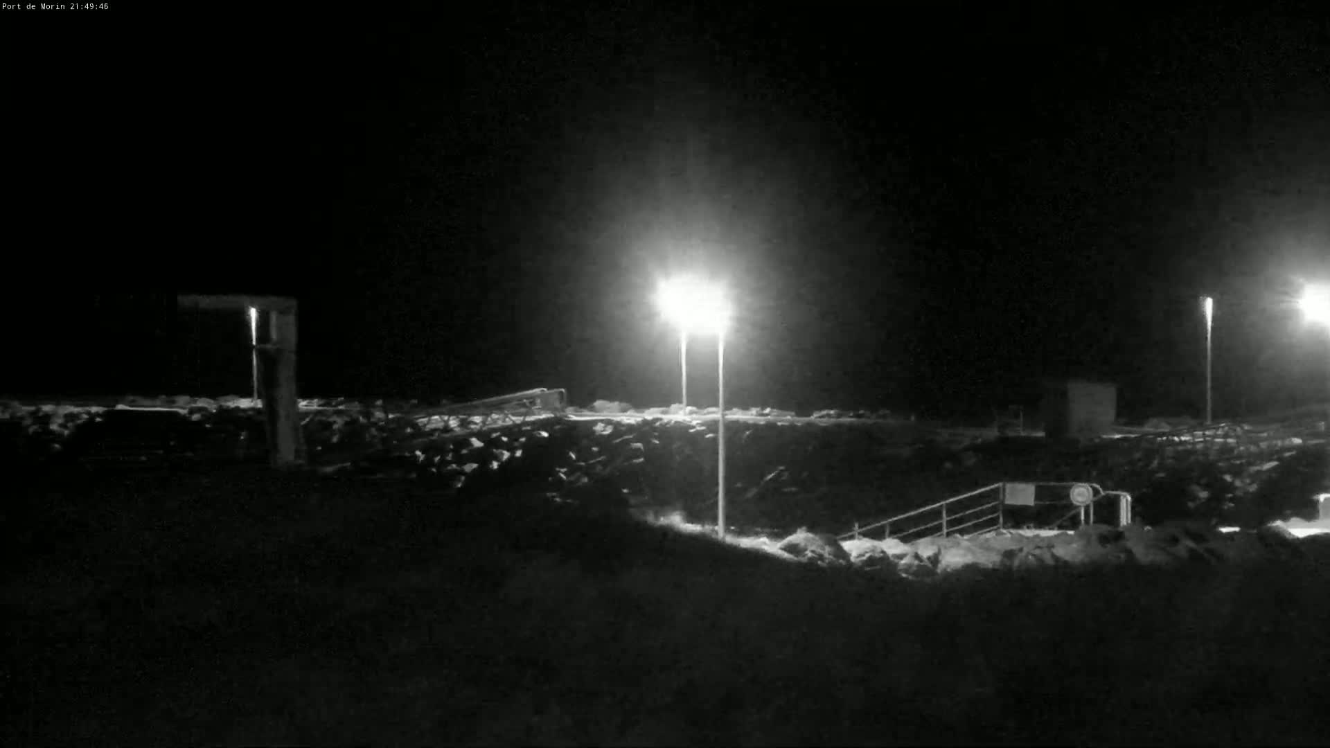 At night, two bright lights illuminate a rocky, snow-covered embankment with a set of stairs leading down.