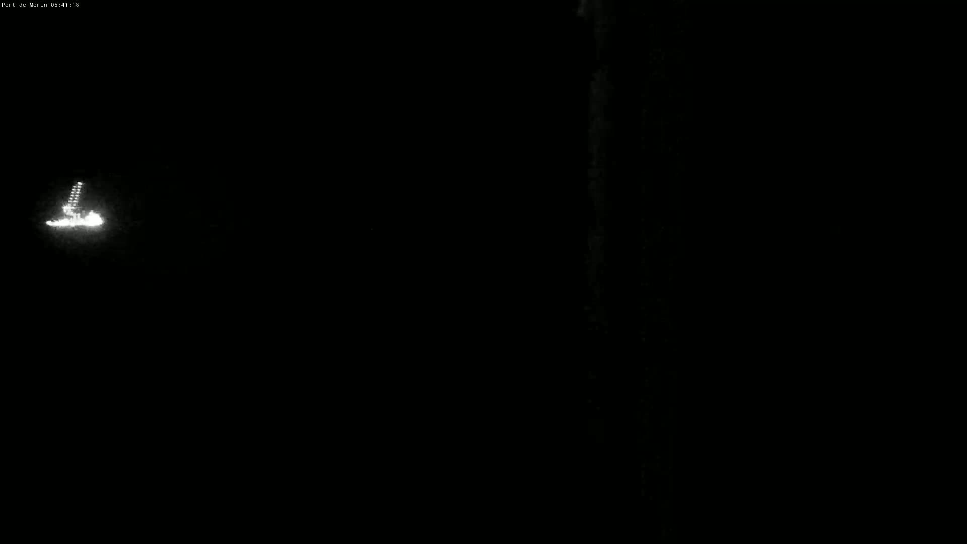 A dimly lit, nighttime scene shows a small cluster of bright lights in the distance to the left.