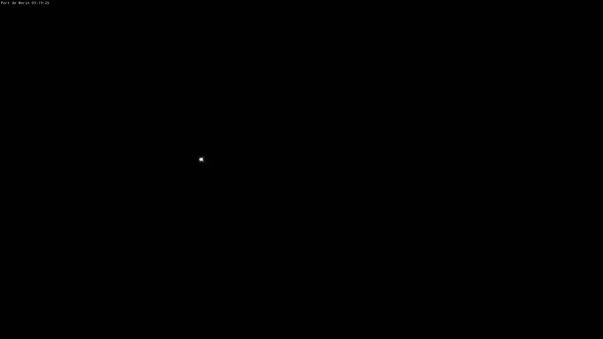 A small, bright light is visible in the center of a completely dark nighttime scene.