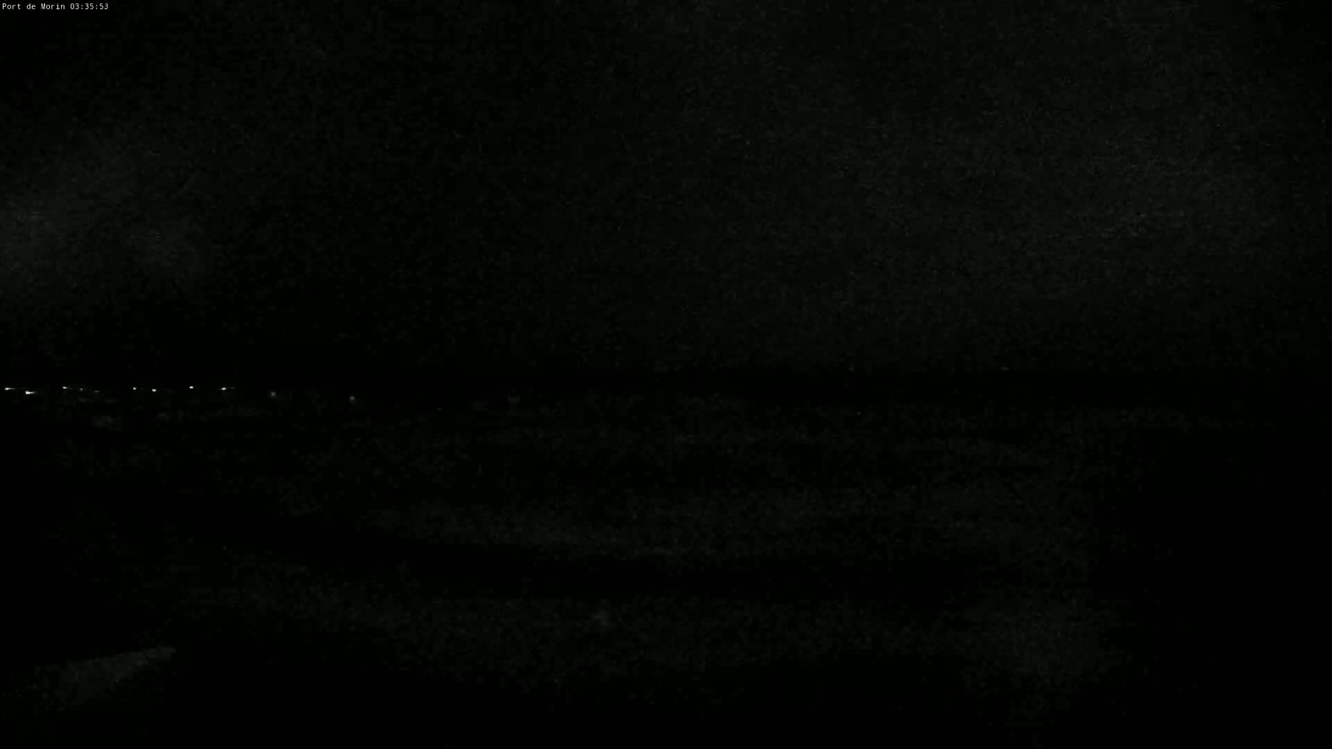 A dark, nighttime scene shows a distant line of faint lights in the horizon.
