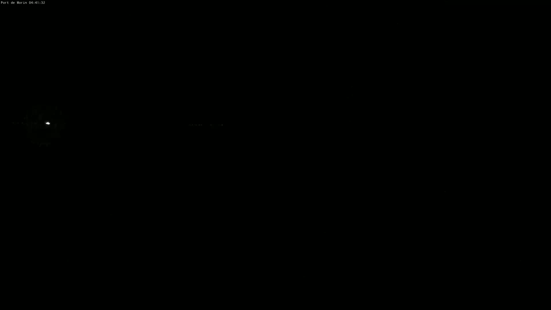 A nighttime, dark scene shows a bright light in the distance and faint, small lights on the horizon.