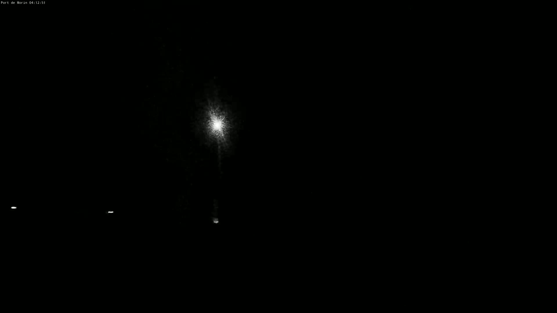A bright light shines in the center of a dark, nighttime scene with two faint lights visible on the left.