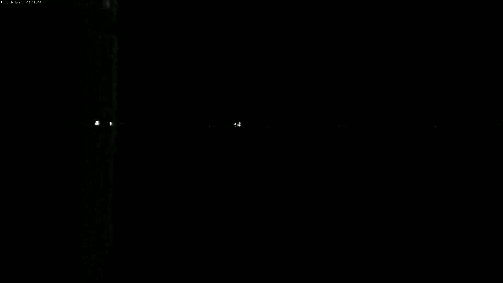 A dark, nighttime scene shows several faint lights in the distance.
