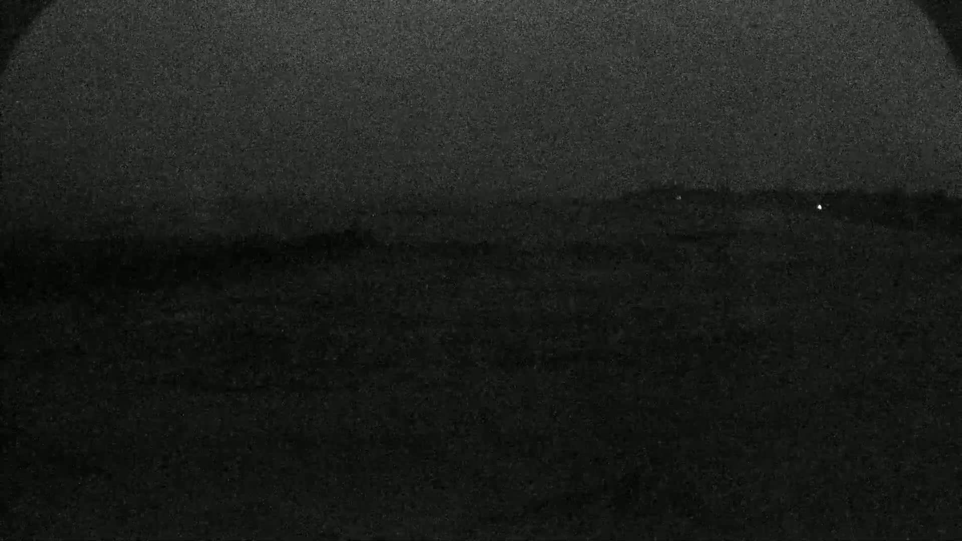 A dark, grainy image shows a mostly obscured landscape under a night sky.