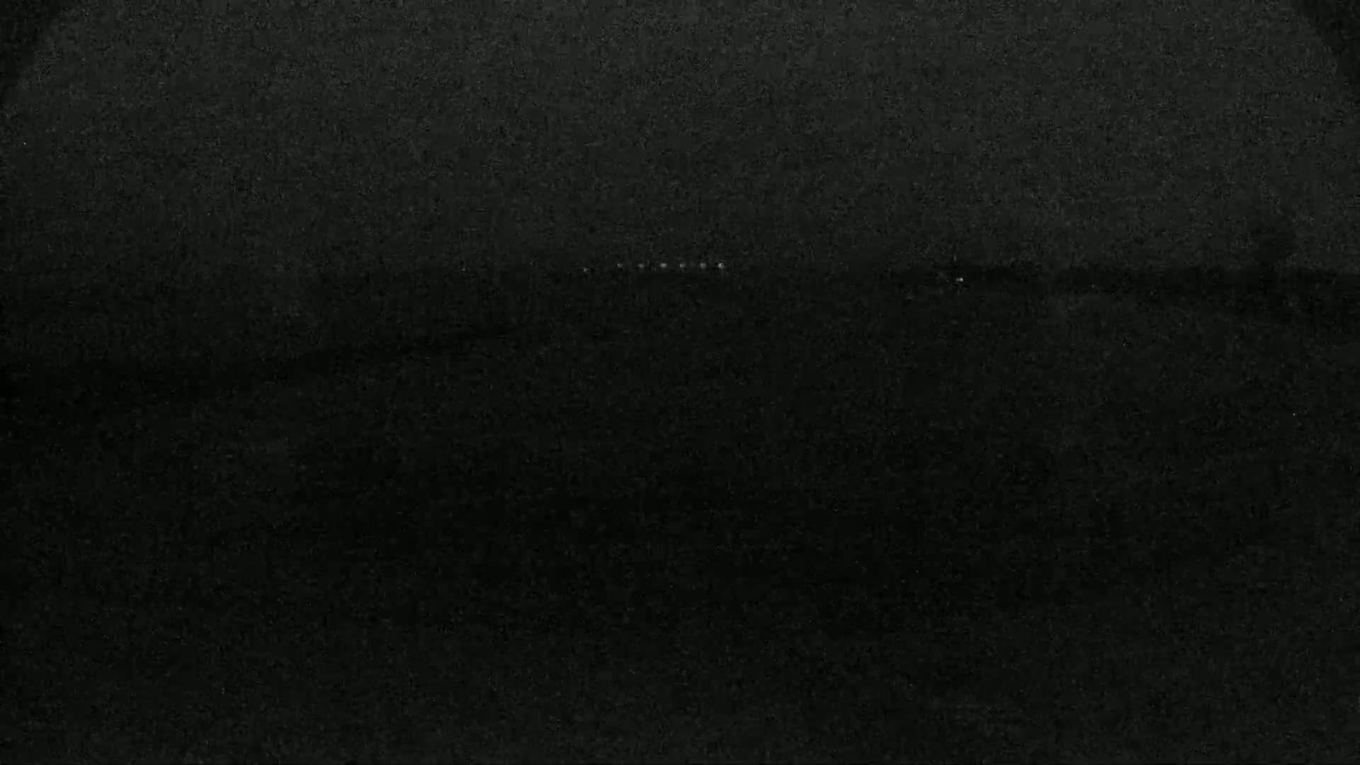 A dark, possibly nighttime, image shows a faint horizontal line of light in the middle of a mostly black background.