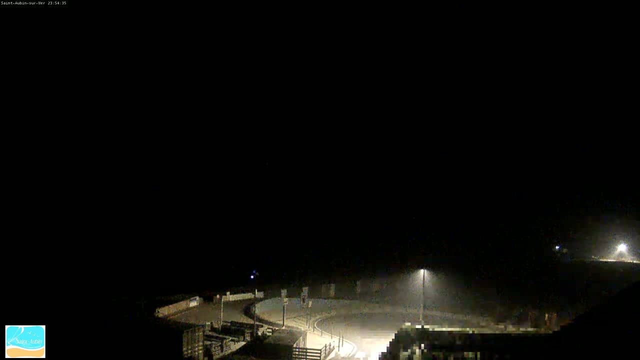 A nighttime, hazy view of a dimly lit roundabout and surrounding area.