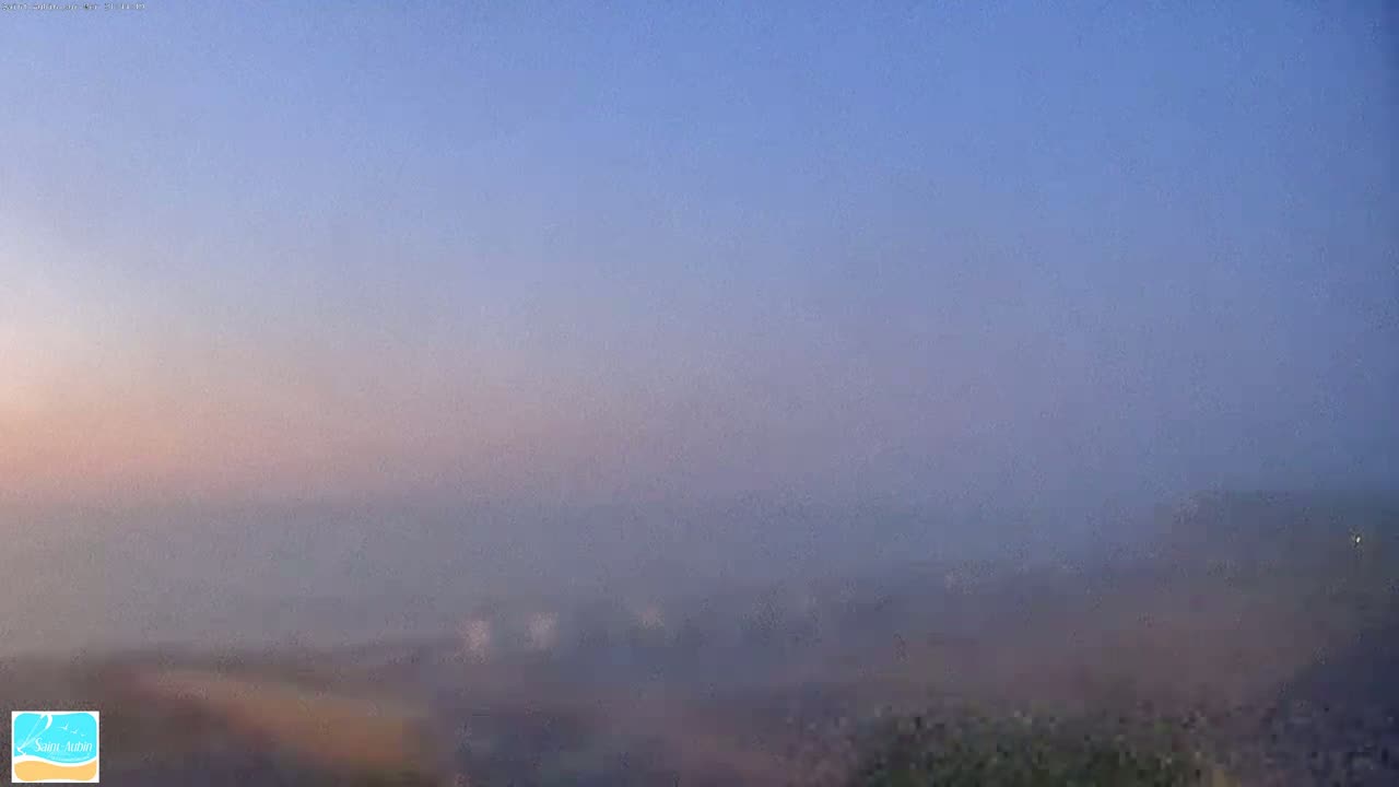 A hazy, foggy landscape is visible under a pale blue, twilight sky.