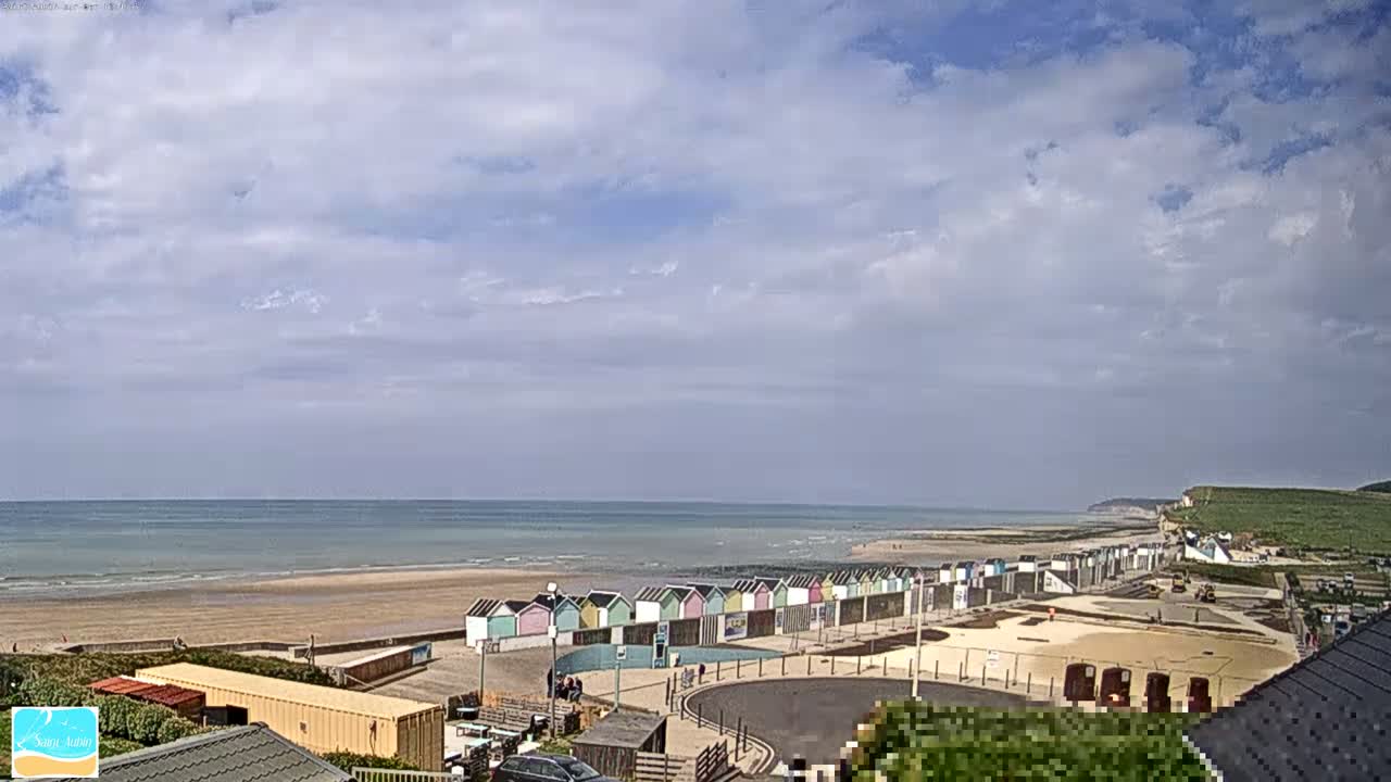 A beach with colorful beach huts is visible under a partly cloudy sky, with a calm sea in the background.