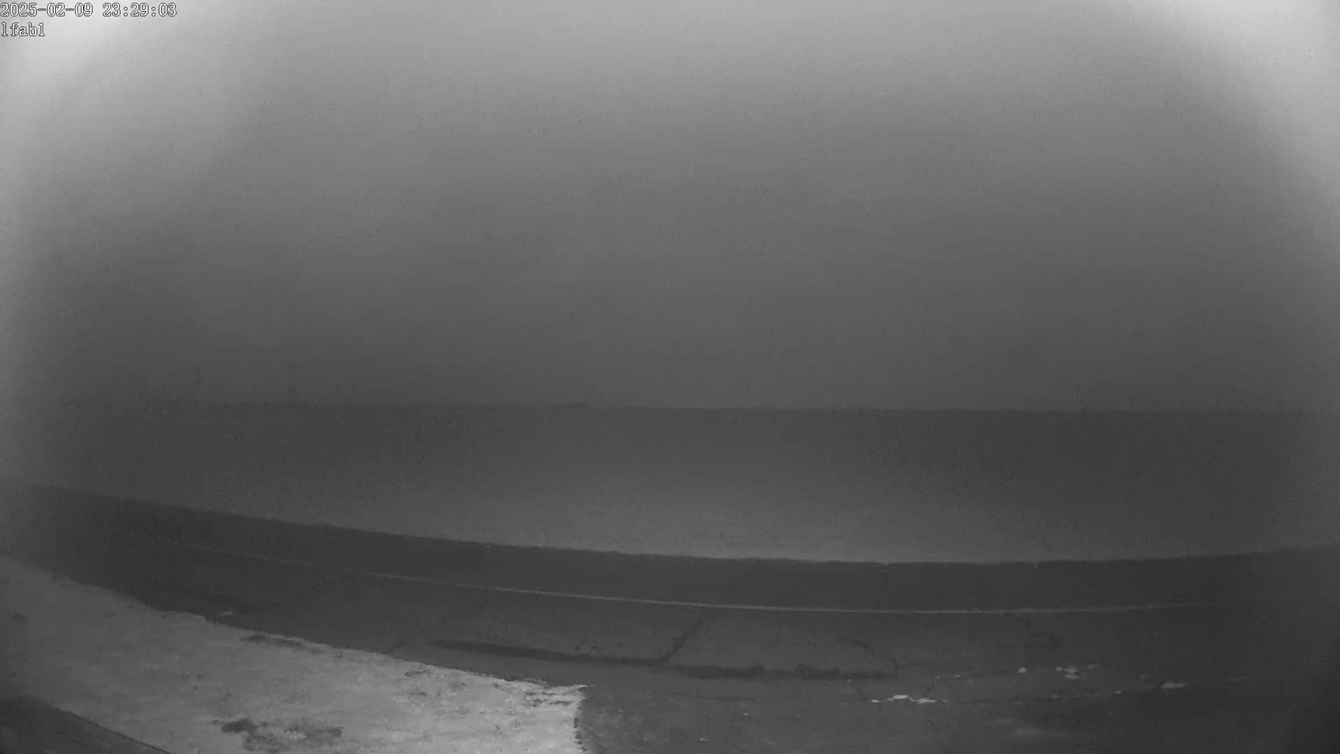 A foggy, low-visibility scene shows a dark road and some snow in the bottom left corner.