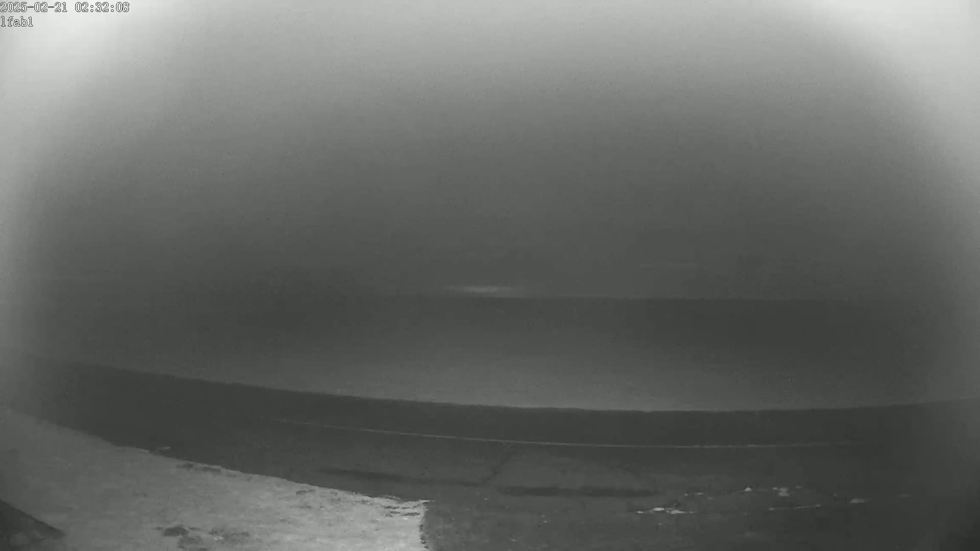 A low-light, foggy view shows a dark expanse of water stretching to a barely visible horizon.