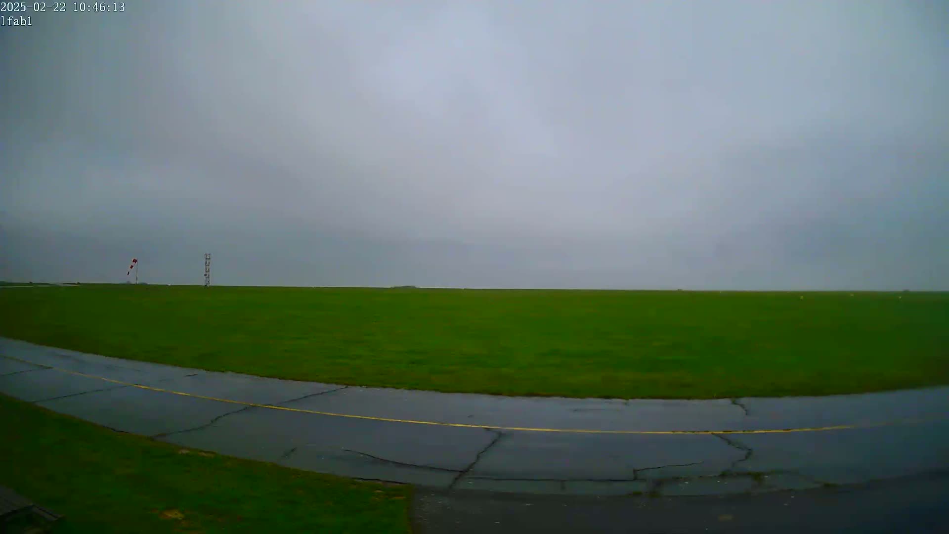 A wet, grassy airfield is visible under an overcast sky.