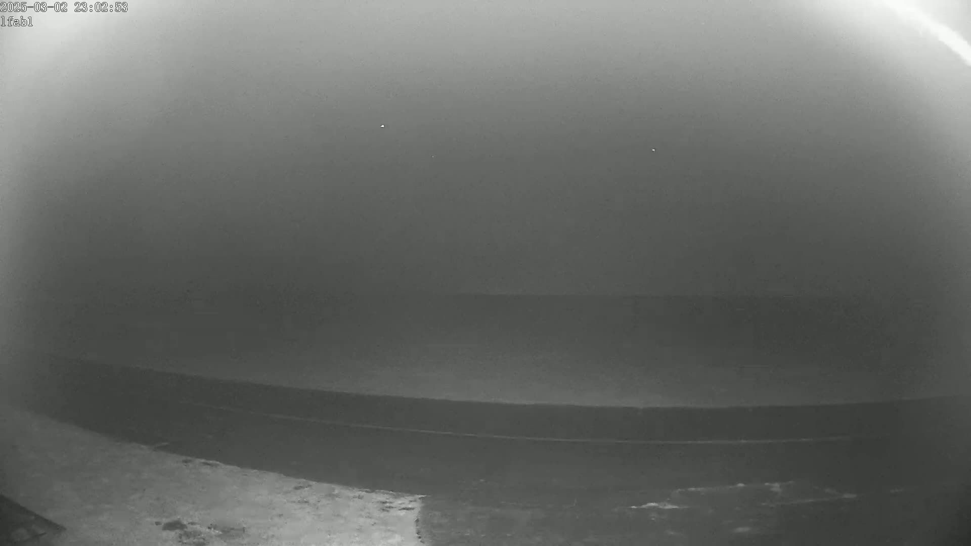 A low-visibility, foggy scene shows a dark, flat surface that appears to be a roadway or dock.