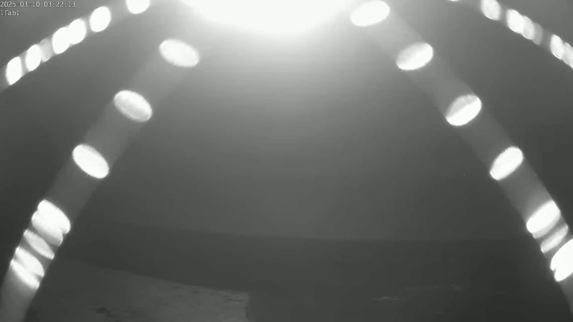 A bright light source creates lens flares in the form of streaks and bright ovals against a dark, hazy background.