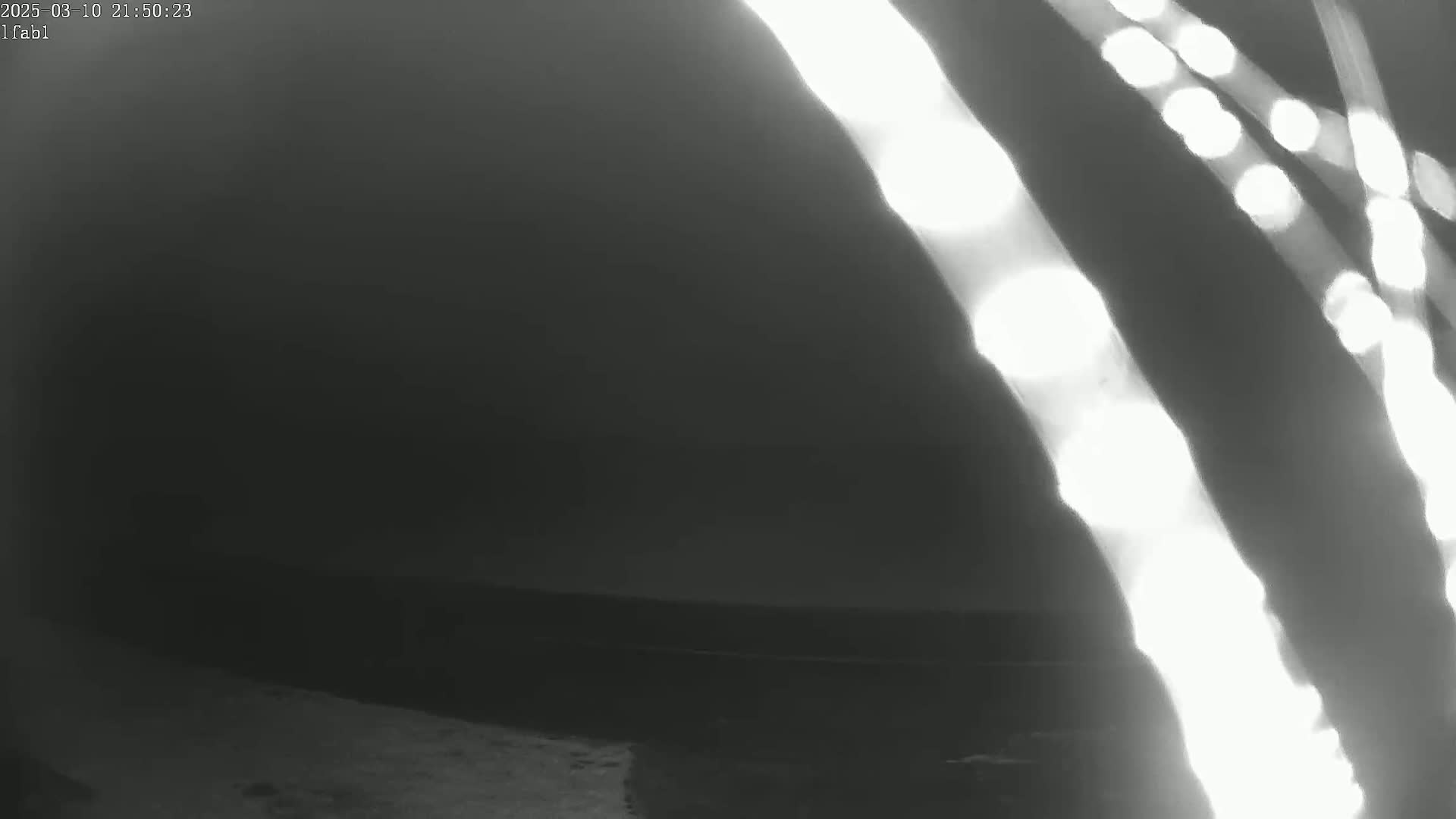 Bright streaks of light shine through the darkness over a dark body of water at night.