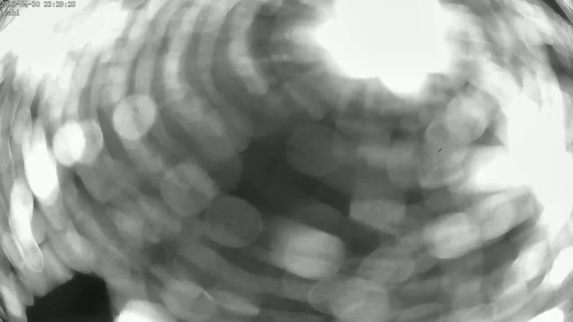 A blurry, grayscale image shows out-of-focus light sources creating a swirling pattern.