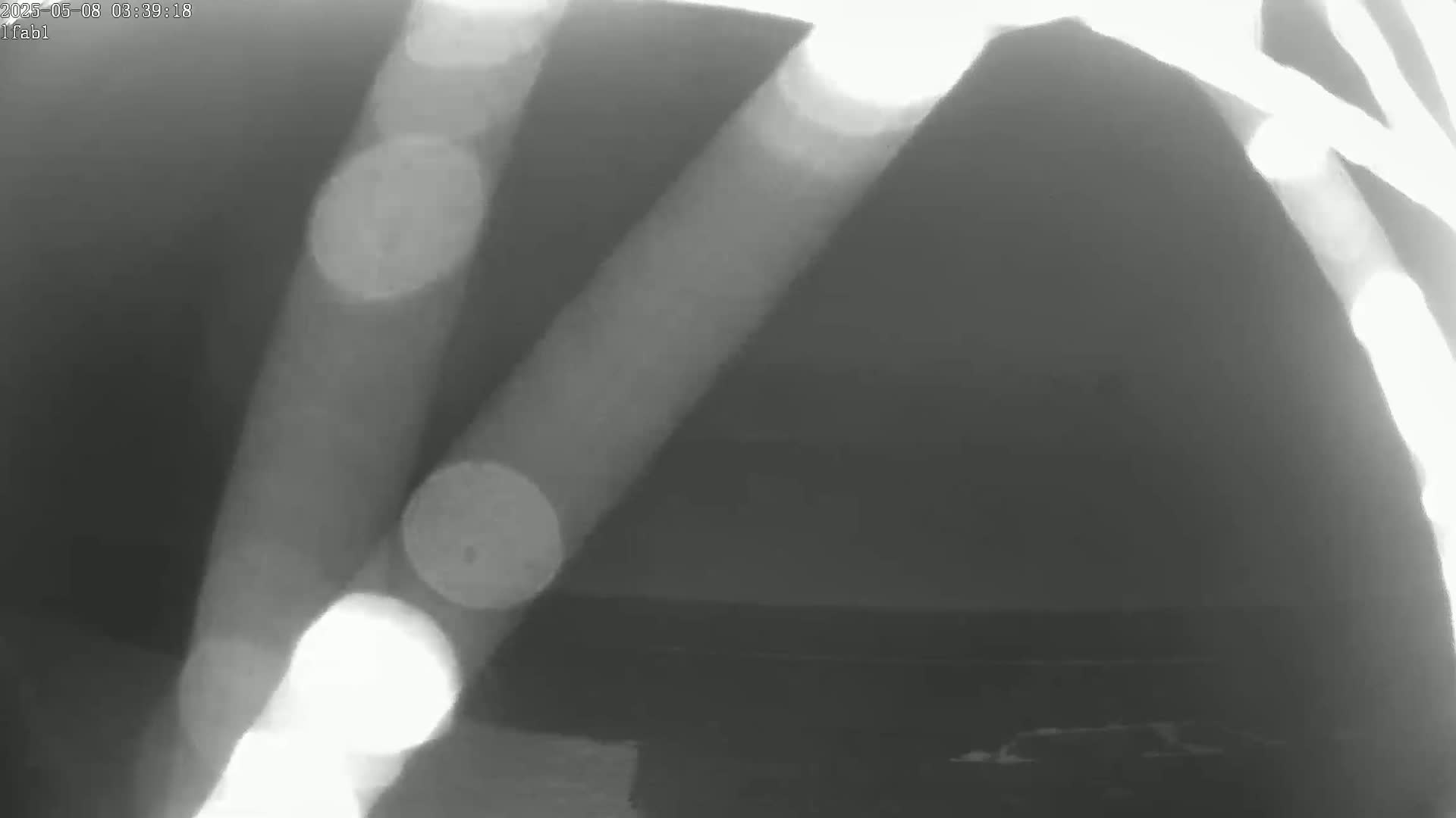 A nighttime, blurry image shows bright streaks of light against a dark background, possibly reflecting off of a body of water.