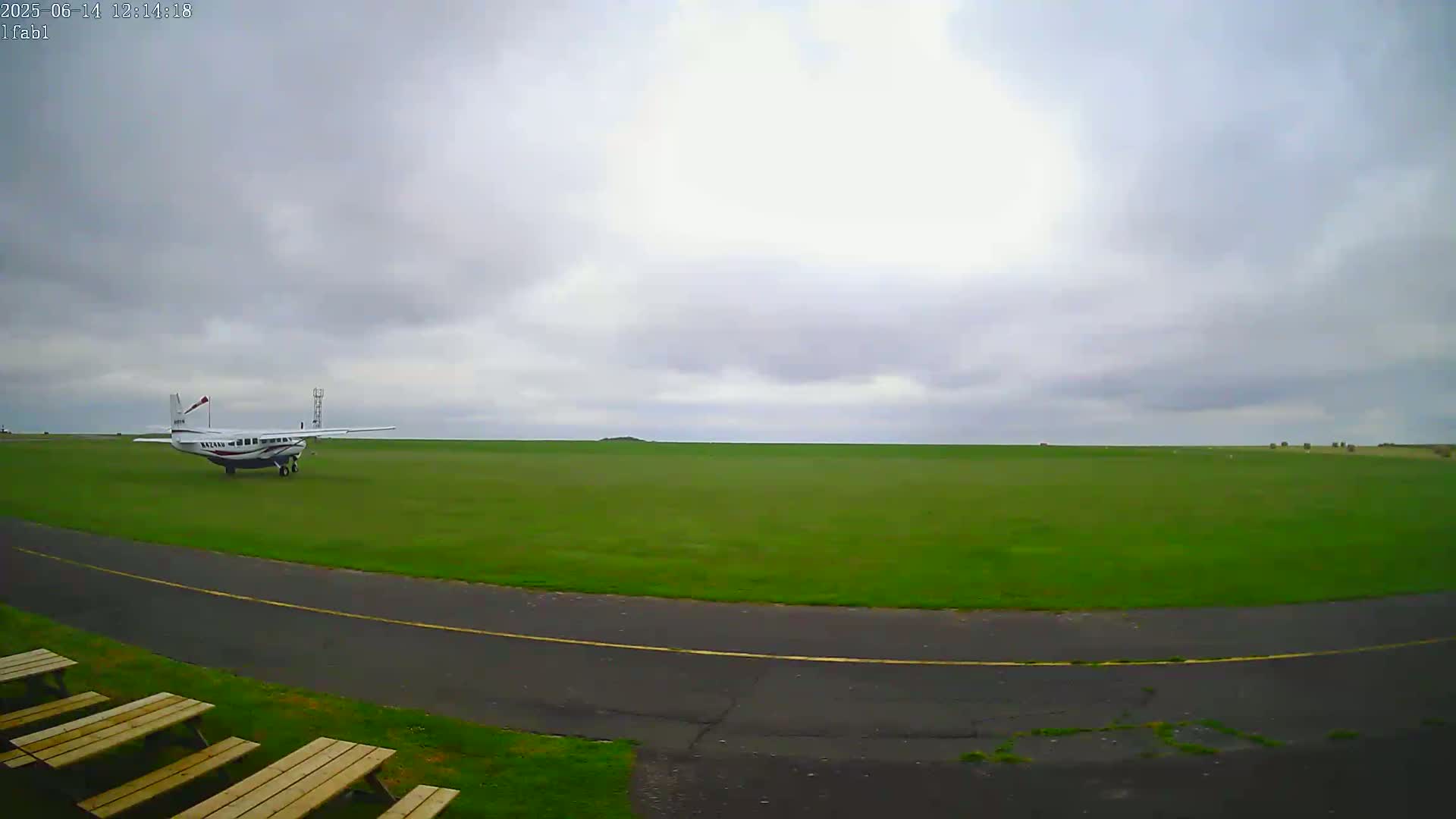A small airplane sits on a grassy airfield under an overcast sky.