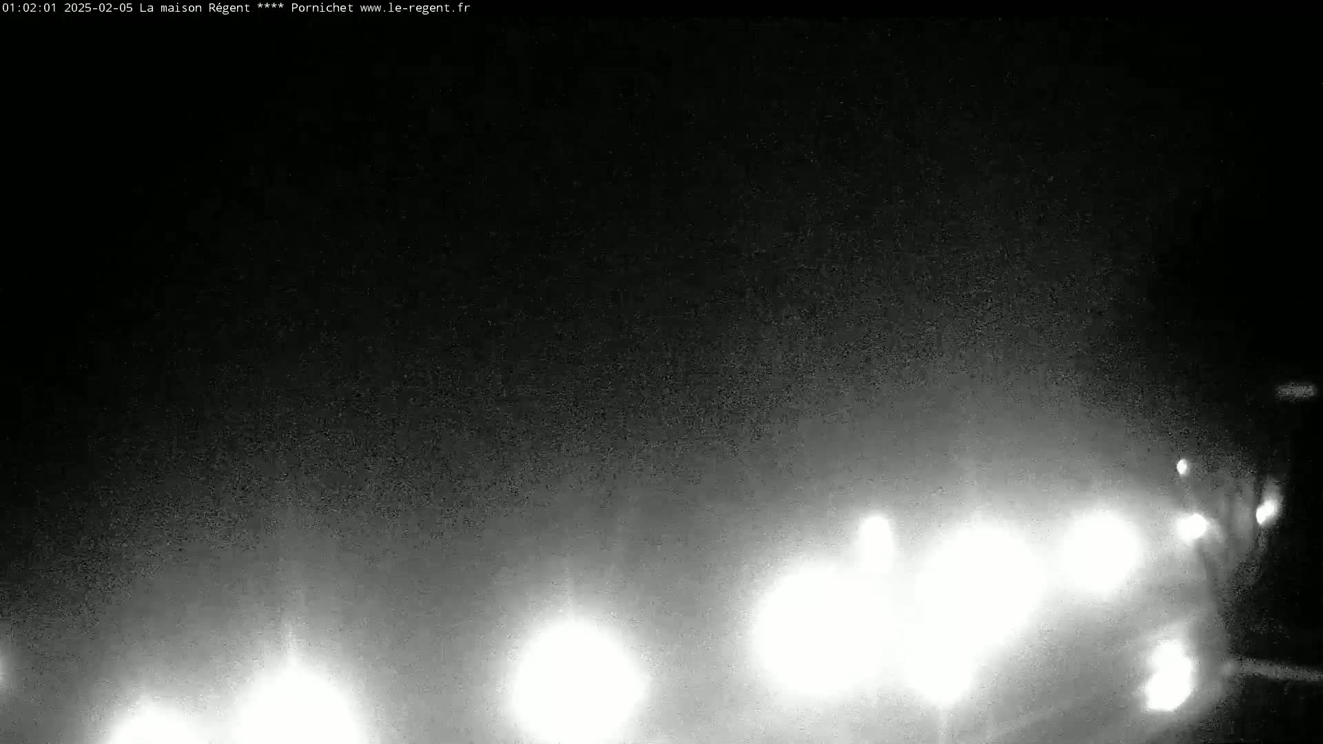 A nighttime, hazy view shows the bright headlights of several vehicles approaching the camera.